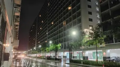 a wet city street at night with a large building at Casa Via at Shore 2 Residences inside SM MOA Complex, Pasay City in Manila