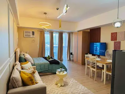 a living room with a couch and a bed and a table at Cozy Unit near Venice Grand Canal Mall McKinley Hill Taguig in Manila