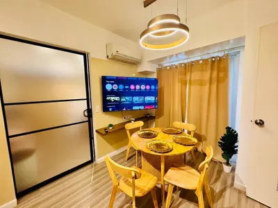 a dining room with a table and chairs and a tv at Cozy Vibes Retreat in Makati in Manila