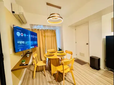 a living room with a table and chairs and a tv at Cozy Vibes Retreat in Makati in Manila