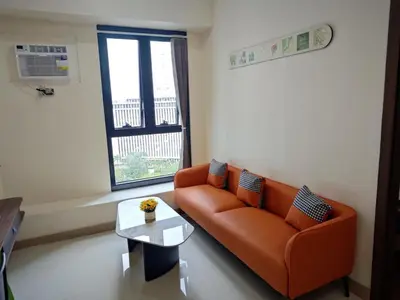 a living room with an orange couch and a table at 1BR near Podium or Marco Polo in Manila
