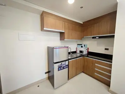 a kitchen with wooden cabinets and a stainless steel refrigerator at 1BR near Podium or Marco Polo in Manila