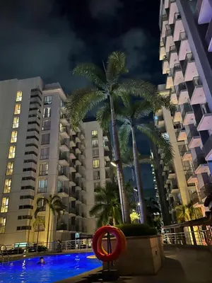 a pool with palm trees and buildings at night at One Tree villas - Hyuna Place, Across NAIA T3 in Manila