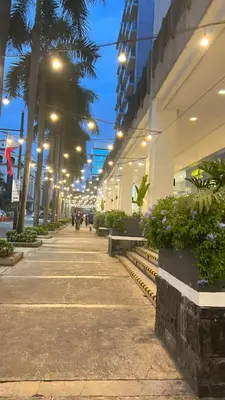 a street with people walking down a sidewalk at night at One Tree villas - Hyuna Place, Across NAIA T3 in Manila