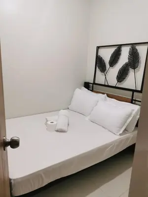 a white bed with white pillows and a headboard at Mao condotel shore 3 residence in Manila