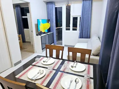 a dining table and chairs in a living room at Suntrus,t Solana Condominium - Ermita, Manila - SM Manila in Manila
