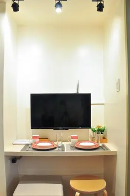 a room with two plates on a table with a television at Modern Zen 1-bedroom with balcony in Manila