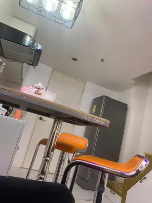 a kitchen with two stools and a counter with a refrigerator at Condo apartment in Manila