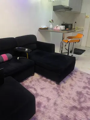 a living room with a black couch and a purple rug at Condo apartment in Manila