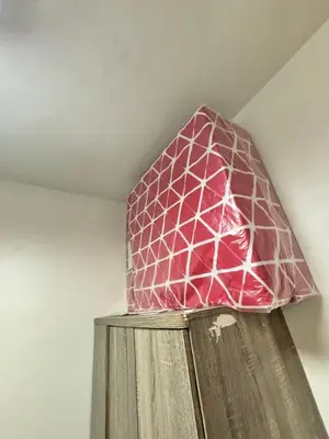 a pink glass lamp sitting on top of a wooden cabinet at Meteoria Staycation in Manila