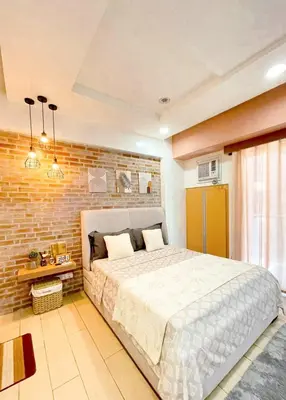 a bedroom with a large bed and a brick wall at Elegant Suite with Balcony l Free wifi and netflix I Across NAIA T3 Airport in Manila