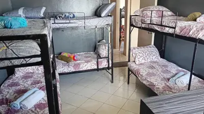 a dorm room with three bunk beds and a chair at BahayMandaragat2 in Manila