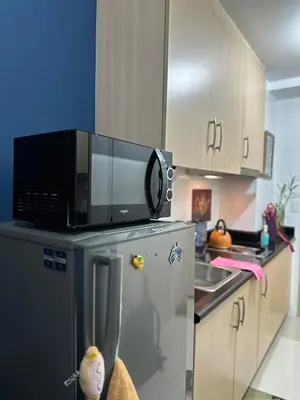 a kitchen with a microwave on top of a refrigerator at Bernie and Adel's Property Rental in Manila
