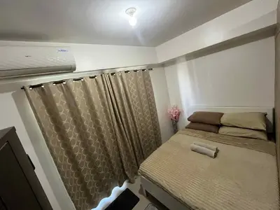 a small bedroom with a bed and a curtain at Cozy 2 Beds Near Mall of Asia in Manila