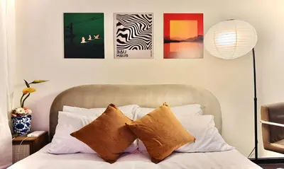 a bedroom with a bed with four pictures on the wall at The Gramercy Residences in Manila