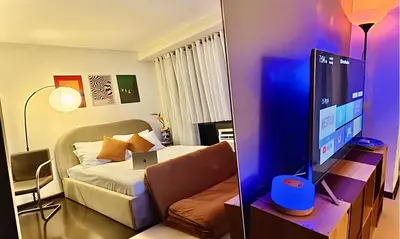 a room with a bed and a tv and a couch at The Gramercy Residences in Manila