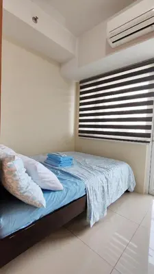 a bedroom with a bed with blue sheets and a window at Condo Staycation Shell Residence in Manila