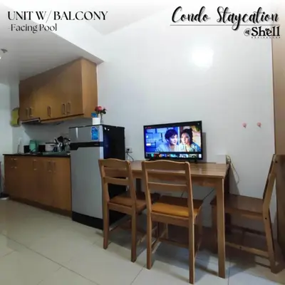 a kitchen with a table with a tv and a kitchen at Condo Staycation Shell Residence in Manila