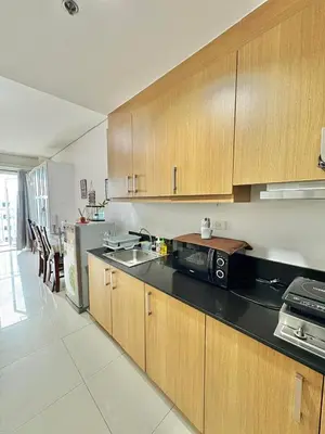 a kitchen with wooden cabinets and a black counter top at Condo Staycation Shell Residence in Manila