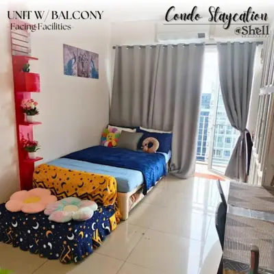 a bedroom with a bed and a couch and a window at Condo Staycation Shell Residence in Manila