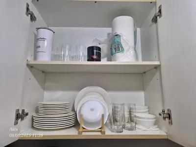 a cupboard filled with plates and glasses and dishes at 1BR Condo at NAIA and Newport Casino Area in Manila