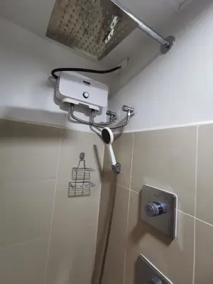 a shower in a bathroom with a light on the wall at Mall of Asia condotel shore 3 residence Aldo Staycation in Manila