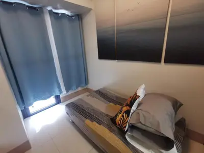 a bedroom with a bed with blue curtains at Mall of Asia condotel shore 3 in Manila