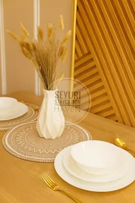 a table with white plates and a vase with wheat at Seyuri Staycation Haven in Manila
