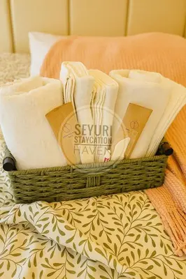 a basket of towels sitting on a bed at Seyuri Staycation Haven in Manila