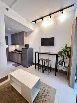 a living room with a table and a kitchen at Prime Location condo near MRT, SM Megamall, BGC! in Manila