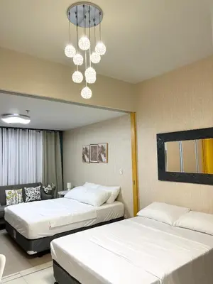 a hotel room with two beds and a chandelier at ONE UPTOWN RESIDENCE BGC 2-bed 1BR in Manila