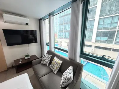 a living room with a couch and a large window at ONE UPTOWN RESIDENCE BGC 2-bed 1BR in Manila