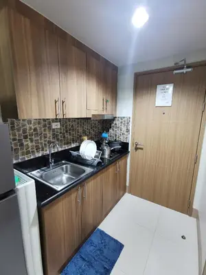 a kitchen with wooden cabinets and a sink and a door at Mall of Asia shore 3 tower 2 residence in Manila