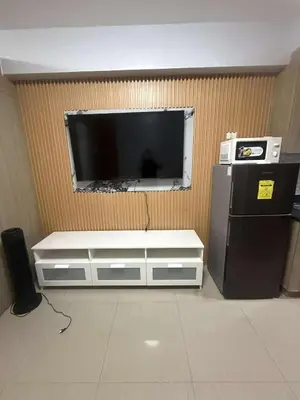 a flat screen tv on a wall next to a refrigerator at Cozy home in Manila