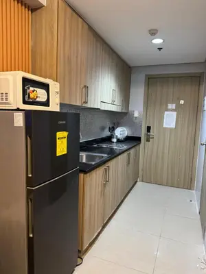 a kitchen with a black refrigerator and wooden cabinets at Cozy home in Manila