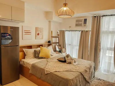 a bedroom with a large bed with a refrigerator at Studio Unit McKinleyHill near Venice Grand Canal in Manila