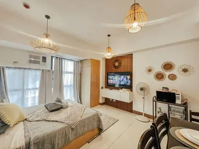 a bedroom with a bed and a tv in it at Studio Unit McKinleyHill near Venice Grand Canal in Manila