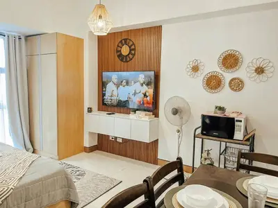 a living room with a television on a wall at Studio Unit McKinleyHill near Venice Grand Canal in Manila