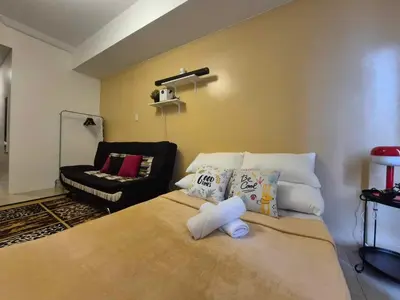 a bedroom with a bed with pillows and a couch at B&C studio in Manila