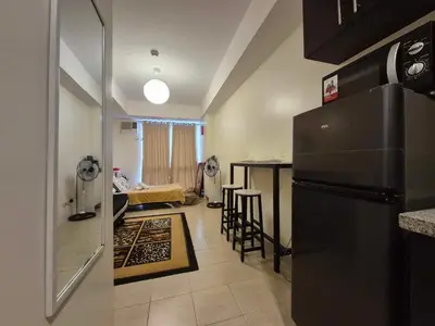 a kitchen with a refrigerator and a living room at B&C studio in Manila