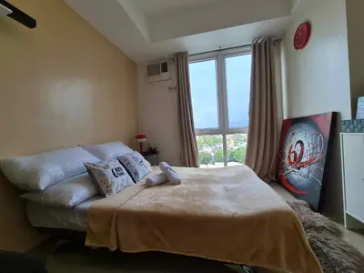 a bedroom with a bed and a large window at B&C studio in Manila