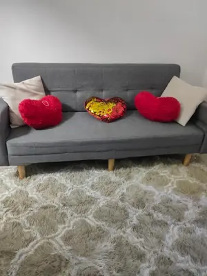 a couch with two heart cushions on it at Shore Residence Tower C2 in Manila
