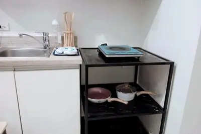a kitchen with a counter with a sink and a shelf with dishes at KL Studio close to Greenbelt in Manila