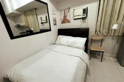 a bedroom with a bed with a mirror and a chair at KL Studio close to Greenbelt in Manila