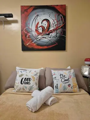 a bed with two pillows and a painting on the wall at B&C Studio Kasara Urban Resort Residences in Manila