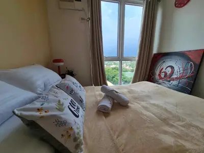 a bedroom with a bed with a large window at B&C Studio Kasara Urban Resort Residences in Manila
