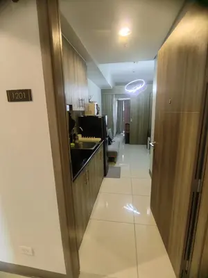 a kitchen with a sink and wooden cabinets and a hallway at AHD Staycation in Manila