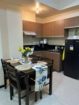 a kitchen with a table and a black refrigerator at Luxury 1BR BayFront Staycation - Free Wi-Fi, Swimming POOL, Near Airport, MOA and PICC in Manila