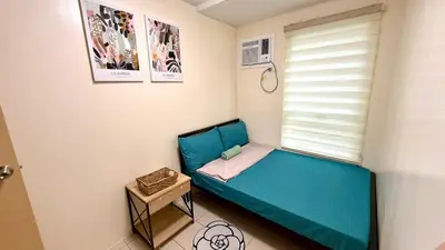 a small bedroom with a blue bed and a window at 1Haven in Pasig CCF Bridgetown in Manila