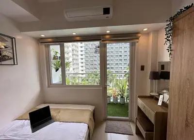 a bedroom with a bed and a window with a laptop at Luxury staycation at prime location Mall of Asia Shell Residences Pasay Tower C in Manila
